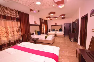 a hotel room with three beds in a room at Petra Guests Hotel in Wadi Musa