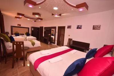 a bedroom with three beds with red and white sheets at Petra Guests Hotel in Wadi Musa