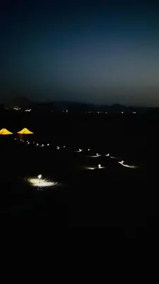 a beach with umbrellas in the dark at night at Rum Jordan camp and tours in Wadi Rum