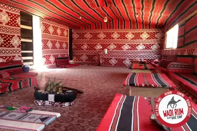 a room with red walls and a room with a table at Wadi Rum Desert Base Camp in Wadi Rum