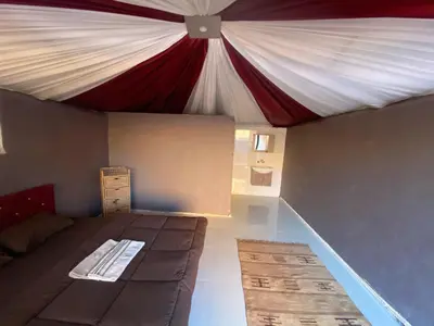 a bed in a room with a red and white tent at Wadi Rum Desert Base Camp in Wadi Rum