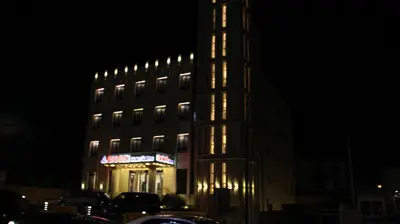 a lit up building with a sign on it at night at Big Ben Hotel Suites in Amman