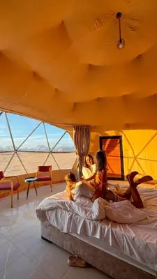 a group of people sitting on a bed in a tent at Taj Wadi Rum camp in Wadi Rum
