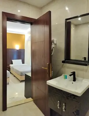 a bathroom with a sink and a mirror and a bed at Petra Town Check-Inn in Wadi Musa