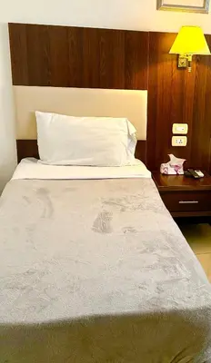 a bedroom with a large white bed and a nightstand at Petra Town Check-Inn in Wadi Musa