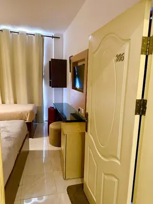 a room with a bed and a desk and a door at Petra Town Check-Inn in Wadi Musa