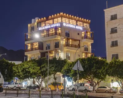 a tall white building with cars parked in front of it at Laverda Hotel in Aqaba