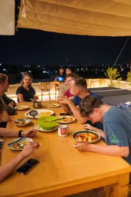 a group of people sitting at a table eating food at Battuta Hostel in Amman