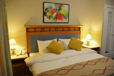 a bedroom with a bed with two lamps and a painting at The Y Hotel in Amman