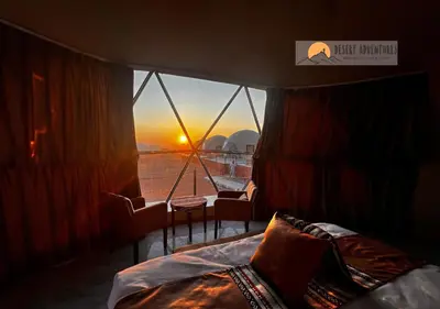 a bedroom with a view of the sunset through a window at Wadi Rum Desert Adventures in Wadi Rum