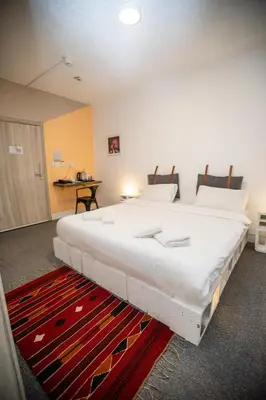 a large white bed in a room with a red rug at Nomads Hotel in Wadi Musa