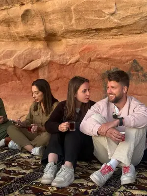 a group of people sitting next to a rock wall at Myra Stars Camp & Tours in Wadi Rum