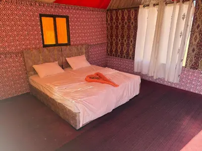 a bedroom with a bed with a red robe on it at Myra Stars Camp & Tours in Wadi Rum