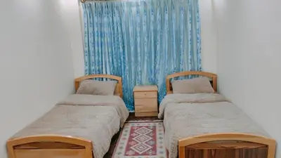 a room with two beds and a blue curtain at Wateen Home in Wadi Musa