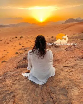 a woman sitting in the desert watching the sunset at Traditions of Wadi Rum camp & jeep tour in Wadi Rum