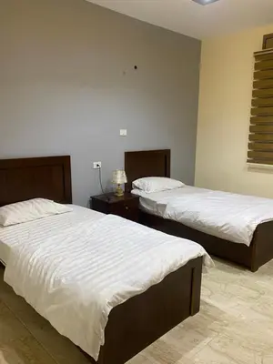 a bedroom with two beds and a table with a lamp at Darkum Apartment in Wadi Musa