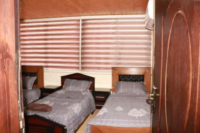 two beds in a small room with a window at Basant Villa in Wadi Musa