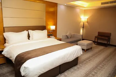 a hotel room with a large bed and a chair at Gloria Hotel Amman in Amman