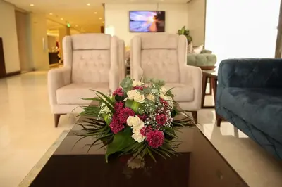 a living room with a table with a bouquet of flowers at Gloria Hotel Amman in Amman