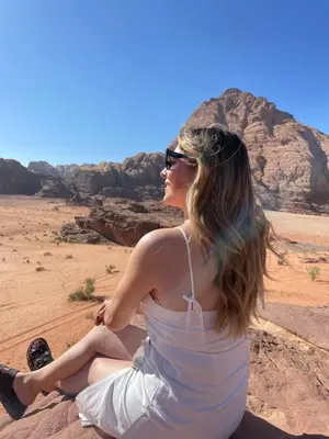 a woman sitting on a rock in the desert at Zarb Desert Camp in Wadi Rum
