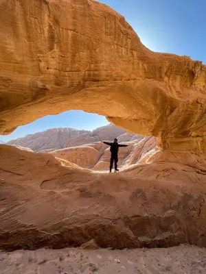 a man standing under an arch in the desert at Zarb Desert Camp in Wadi Rum