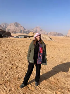 a woman standing on the sand in the desert at Zarb Desert Camp in Wadi Rum