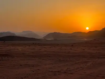 a sunset in the desert with the sun setting at Wadi rum Bedouin Experience in Wadi Rum