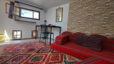 a living room with a red couch and a brick wall at Our Villa's Pine Cottage - HQ Budget Stay - Wonderful horizon view of Jerash in Jerash