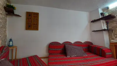 a living room with a red couch in a room at Our Villa's Pine Cottage - HQ Budget Stay - Wonderful horizon view of Jerash in Jerash