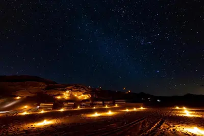 a night view of a desert with a starry sky at Candle light camp & tours in Wadi Rum