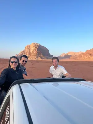 three people standing next to a car in the desert at Candle light camp & tours in Wadi Rum