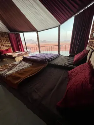 a bed in a tent with a view of the desert at Candle light camp & tours in Wadi Rum