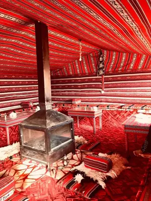 a living room with a fireplace in a red room at Wadi Rum Bedouin Heart in Wadi Rum