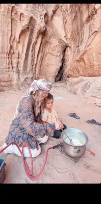 a woman and a baby sitting next to a bowl at Wadi Rum Bedouin Heart in Wadi Rum