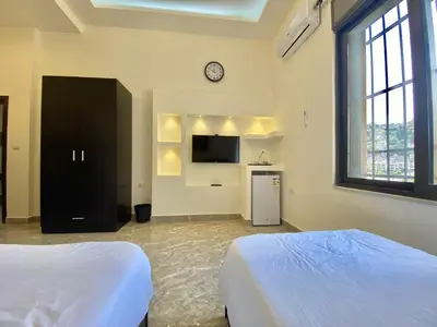 a large bedroom with two beds and a tv at Villa Mira Guesthouse 1 - Downtown Central Amman - AL DIYRIH in Amman