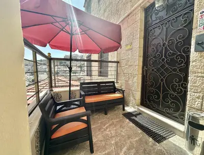 a balcony with a table and chairs and an umbrella at Villa Mira Guesthouse 1 - Downtown Central Amman - AL DIYRIH in Amman