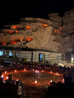 a group of people sitting in front of a rock wall at Faisal Wadi Rum Camp in Wadi Rum