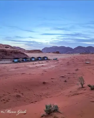 a desert with a group of houses in the desert at Discover the life of Wadi Rum camp in Wadi Rum