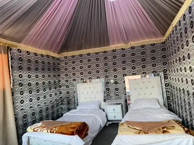 two beds in a room with a wall at Discover the life of Wadi Rum camp in Wadi Rum