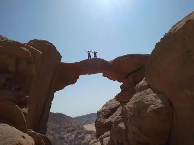 two people standing on top of a rock formation at Wadi Rum night soul Camp in Wadi Rum