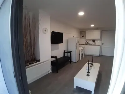 a living room with a white table and a kitchen at The Place in Madaba