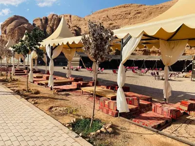 a group of umbrellas on a beach with rocks at Al Sultana Luxury Camp in Wadi Rum