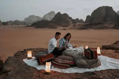 a man and woman sitting on a blanket in the desert at Quite bedouin life in Wadi Rum