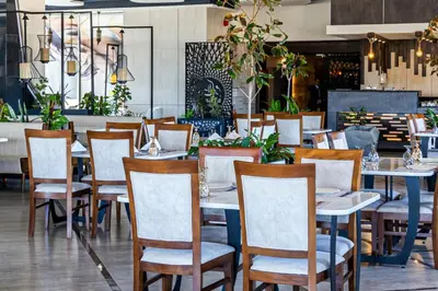 a restaurant with white tables and chairs and plants at Opal Hotel Amman in Amman