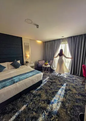 a woman in a white dress standing in a hotel room at Opal Hotel Amman in Amman