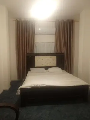 a bed in a bedroom with a light above it at Jarajreh Apartments/ Hotel in Kerak