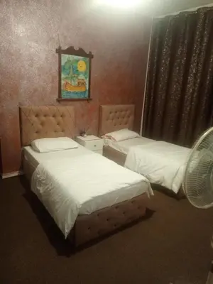 two beds in a hotel room with a fan at Jarajreh Apartments/ Hotel in Kerak