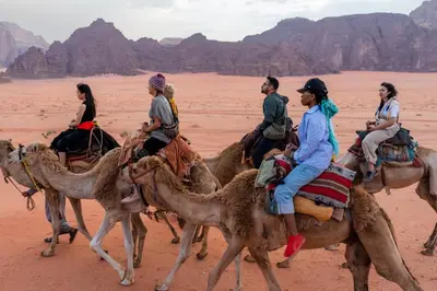 a group of people riding on camels in the desert at Walid Bedouin Camp in Wadi Rum