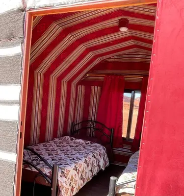 a bed in a room with a red wall at Walid Bedouin Camp in Wadi Rum