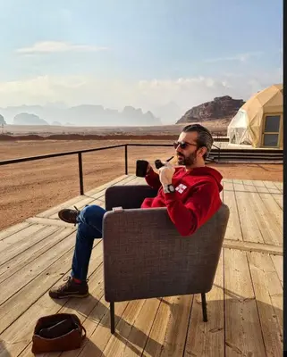 a man sitting in a chair taking a picture of the desert at Rum warm bubble camp in Wadi Rum